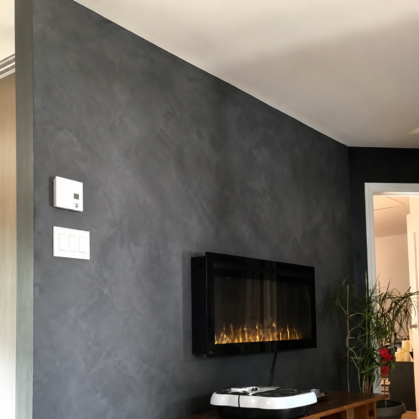 Après — même mur fini à la chaux, gris anthracite nuagé, foyer encastré